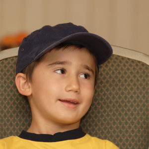 Boy with baseball cap looking to side