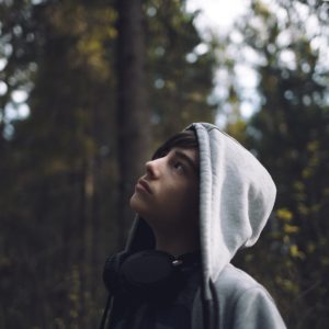 Teenage boy looking up at treetops
