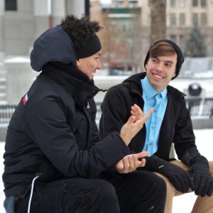 Two teenage boys sitting outside in snow